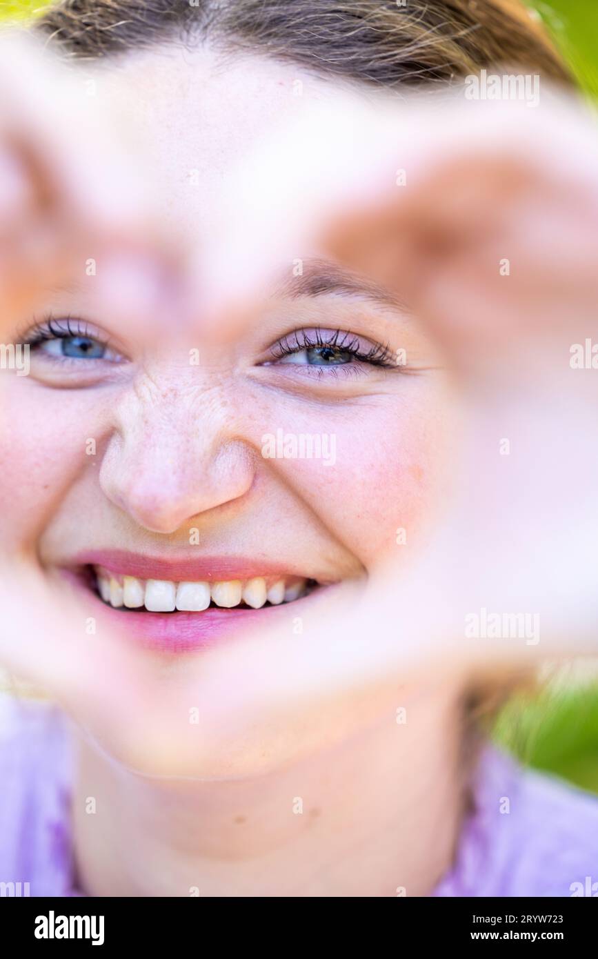 Connessione sentita: Bella donna che abbraccia amore e gioia, ritratto di una bella giovane donna che guarda attraverso il simbolo del cuore Foto Stock