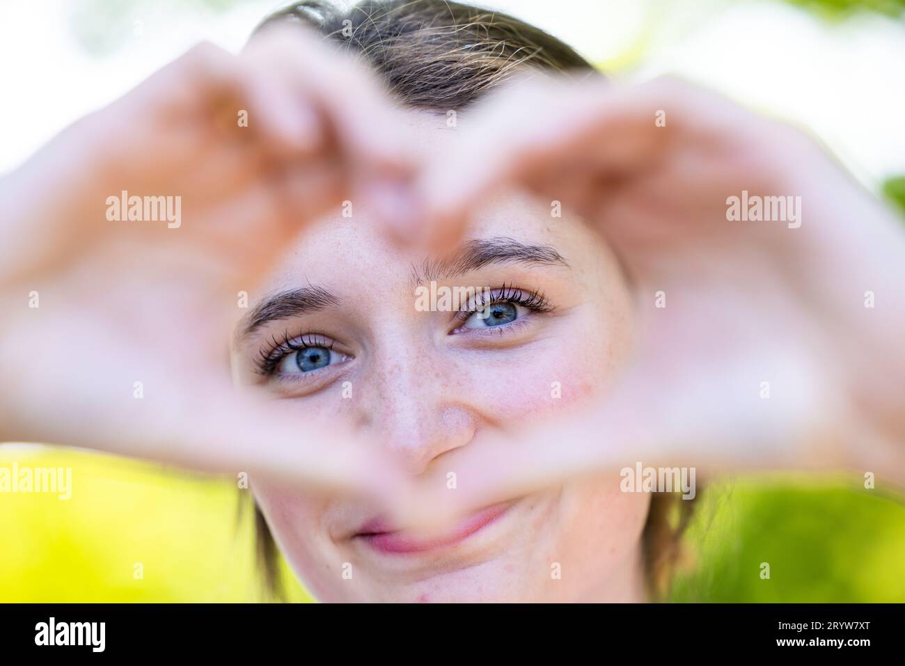 Connessione sentita: Bella donna che abbraccia amore e gioia, ritratto di una bella giovane donna che guarda attraverso il simbolo del cuore Foto Stock