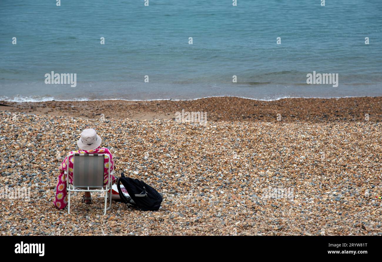 Donna anziana che si rilassa su una spiaggia di ciottoli. Vacanze estive, tempo libero Foto Stock