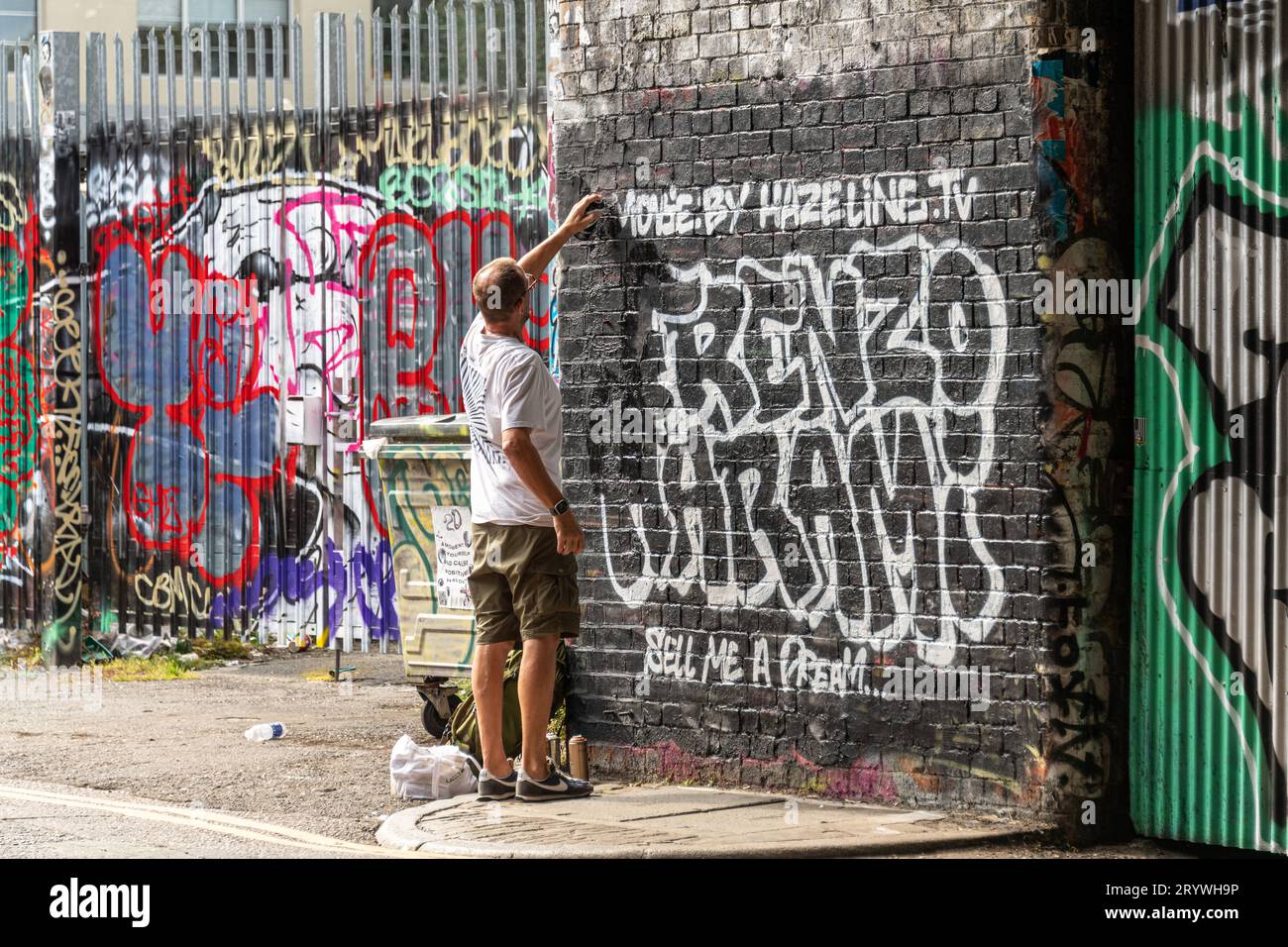 Uno spray di graffiti dipinge un muro a Shoreditch East London. Foto Stock