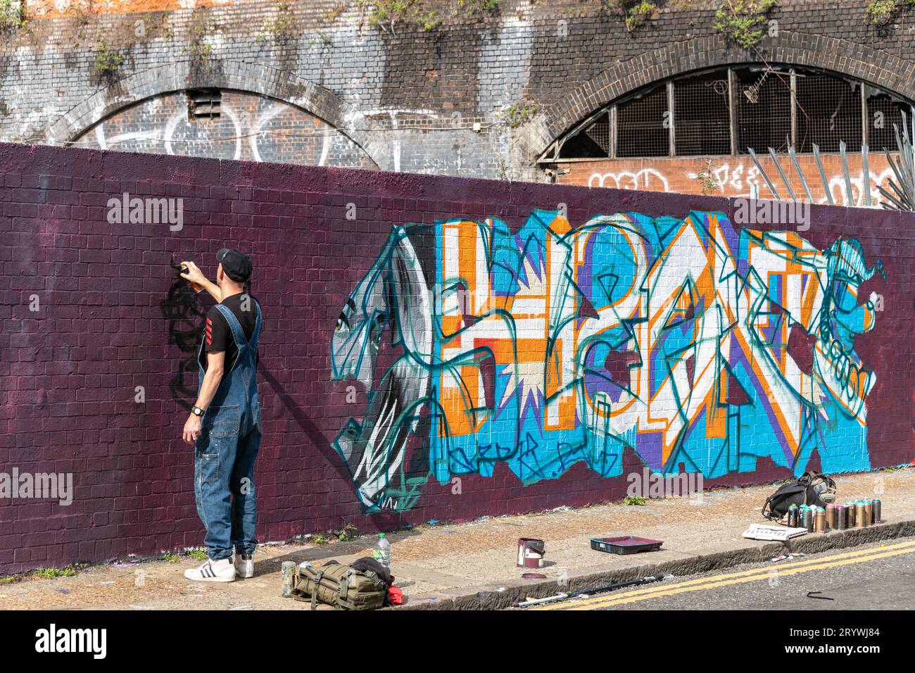 Uno spray di graffiti dipinge un muro a Braithwaite St Shoreditch, Londra, E1. Foto Stock