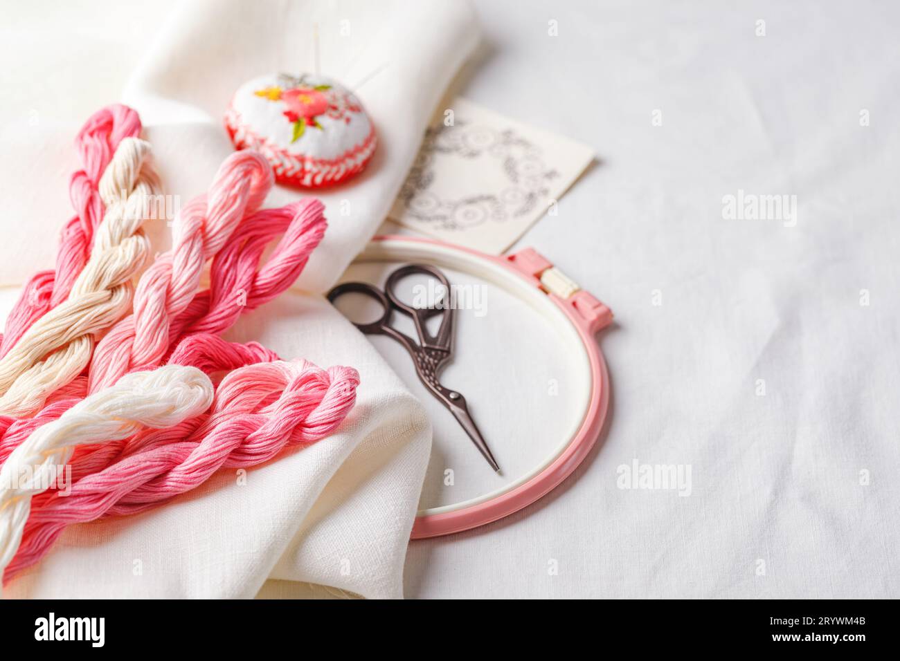 Set da ricamo. Tessuto in lino, motivi ricamati, canestro da ricamo, fili colorati e aghi. Foto Stock