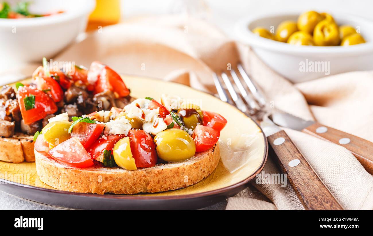 Deliziose bruschette con funghi, formaggio azzurro, olive e pomodori Foto Stock