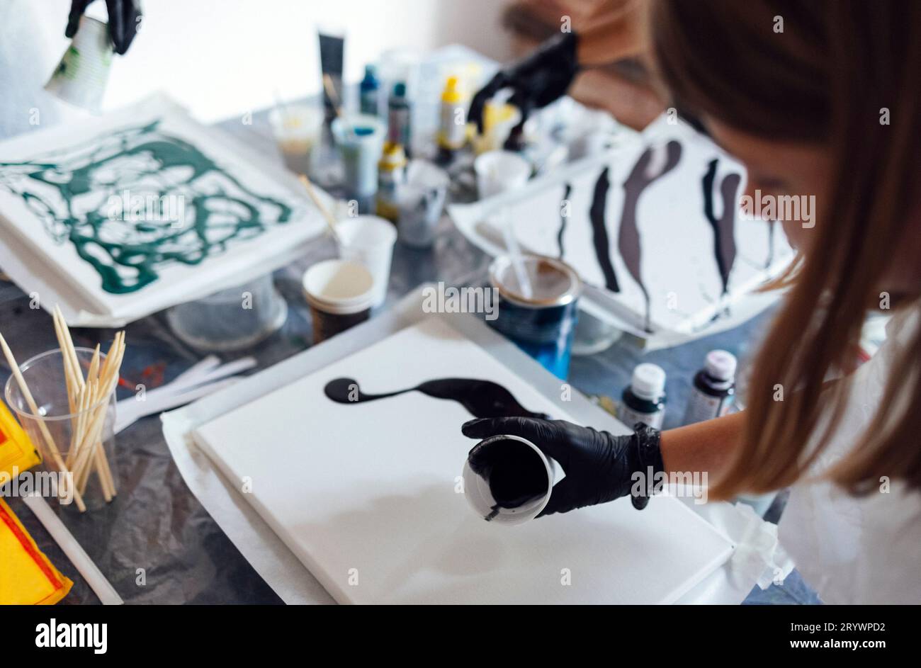 Master class su un versamento di fluido acrilico. Giovani donne dipingono con acrilico liquido in un laboratorio d'arte Foto Stock