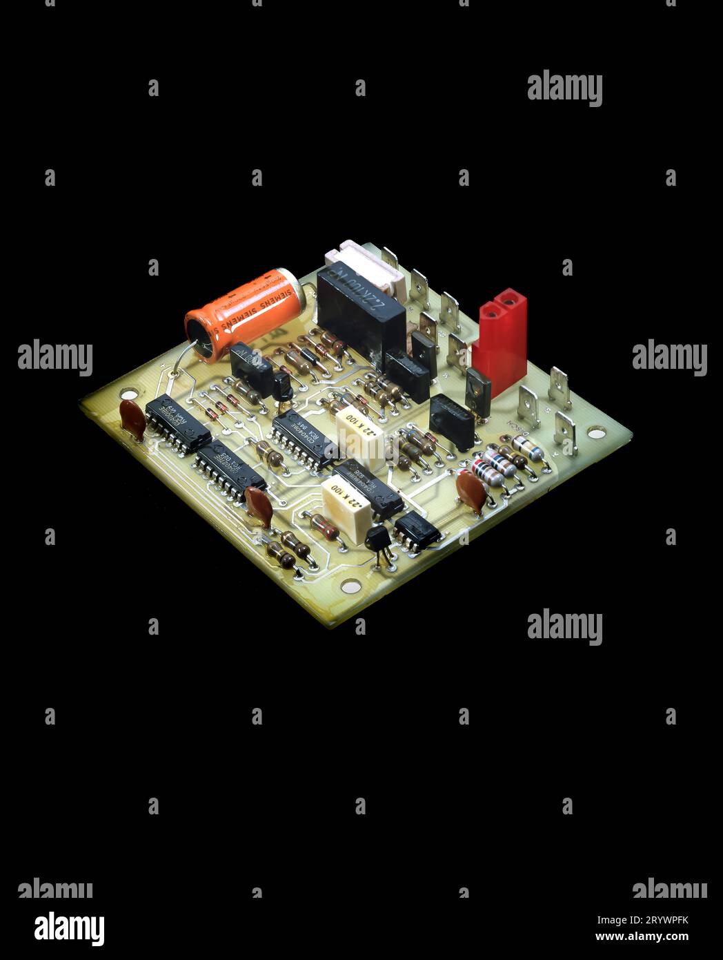 Scheda a circuito stampato elettronico (PCB) con circuiti integrati, condensatori e connettori isolati su sfondo nero, dettagli sui componenti tecnologici. Foto Stock