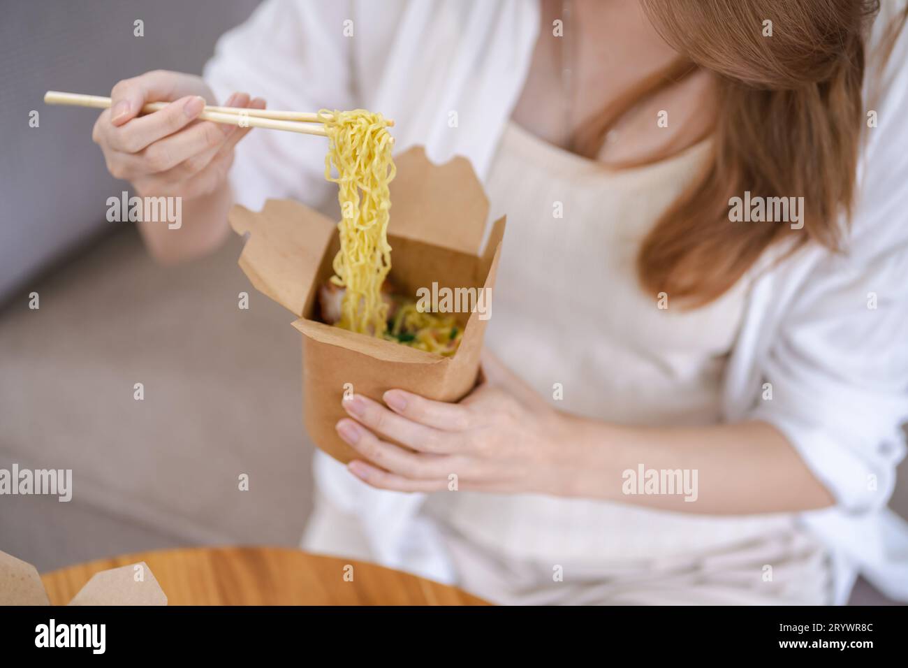 Donna asiatica con cibo da asporto e bevande a casa. Consumo eatingÂ consegna a domicilio di cibo. gusta una deliziosa consegna da asporto Foto Stock