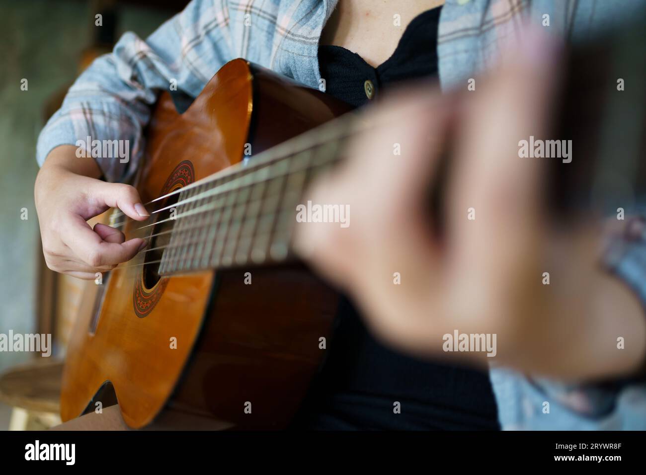 Le mani di una giovane donna felice che suona la chitarra acustica da solo compongono una lezione di canto strumentale su come suonare la chitarra. Foto Stock