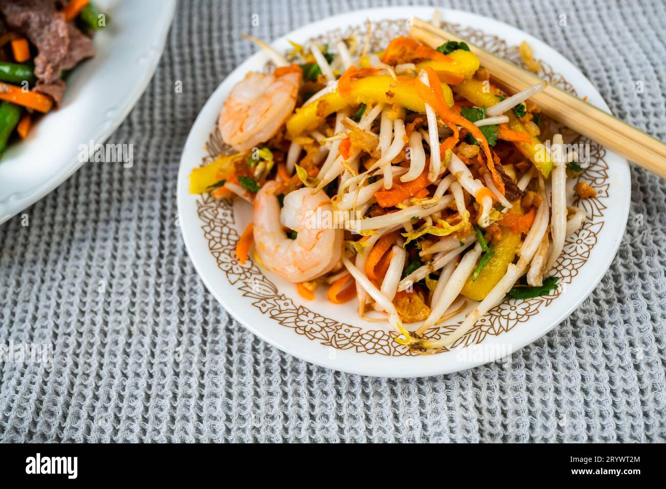 Insalata di mango con verdure e gamberi, bacchette. Antipasto vietnamita. Foto Stock