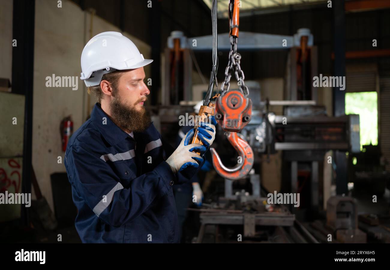 Due tecnici che ispezionano e testano il funzionamento delle gru di sollevamento in impianti industriali pesanti. Foto Stock