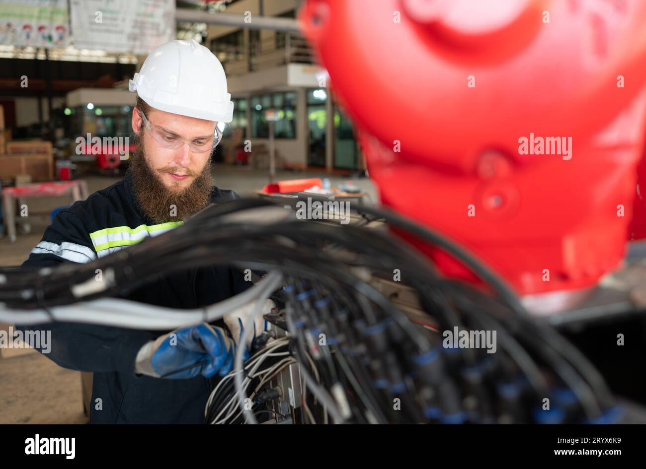 Ingegnere elettrico con la missione di installare un sistema elettrico del braccio robotizzato Foto Stock