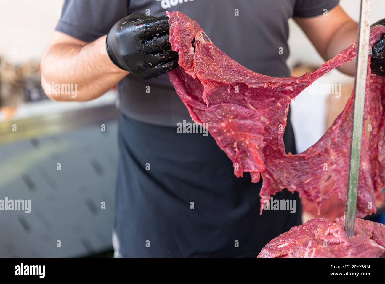 Il maestro sta preparando il kebab turco per cucinare con carne rossa, carne di kebab doner cruda, gyros greci sullo spiedo in un ristorante. Foto di alta qualità Foto Stock