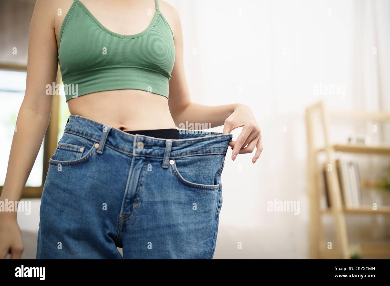 Donna asiatica dietetica perdita di peso. Donna magra in jeansÂ oversize Foto Stock