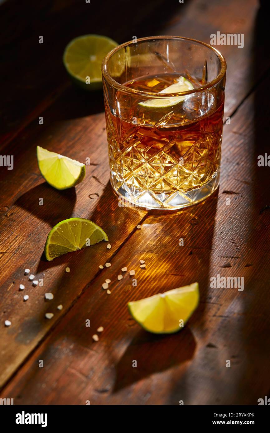 Bevanda estiva, whisky, tequila o cognac, limonata, cocktail alcolico o analcolico con limes e sale su un tavolo di legno Foto Stock