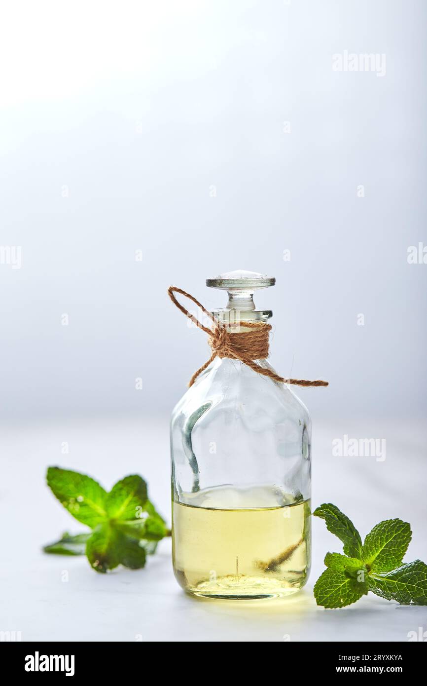 Bottiglia con olio essenziale di menta e foglia verde su sfondo bianco. Ingredienti naturali biologici per cosmetici, cura della pelle, corpo tre Foto Stock