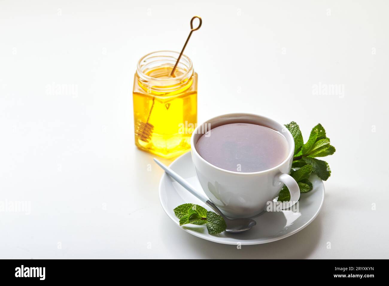 Tè nero in tazza bianca con foglie di menta e miele. Tè calmante e rivitalizzante, anti-stress e relax Foto Stock