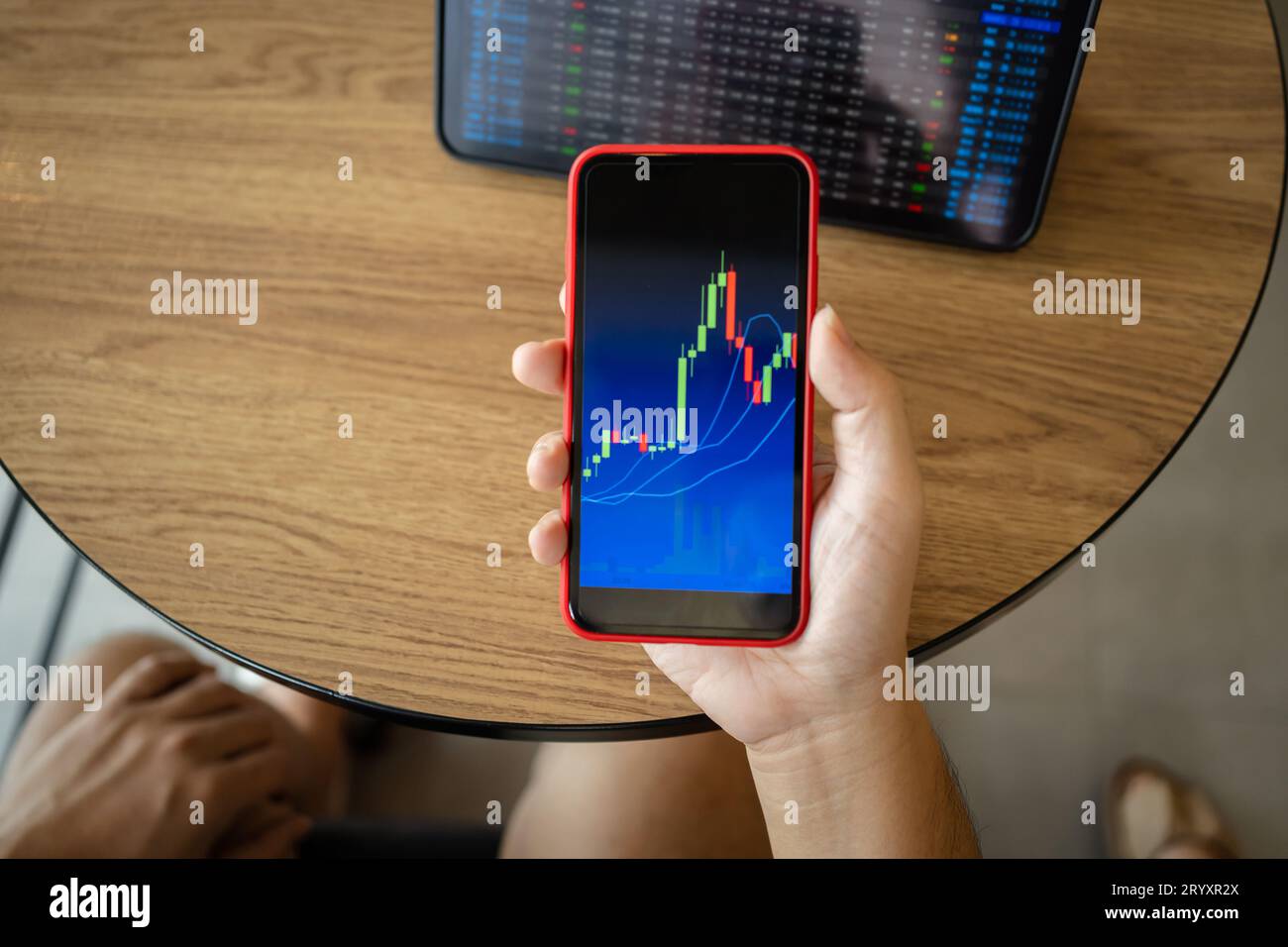 Uomo che tiene il telefono e guarda il grafico a candelabro adatto per il mercato azionario forex o per il trading di criptografia di investimenti finanziari Foto Stock