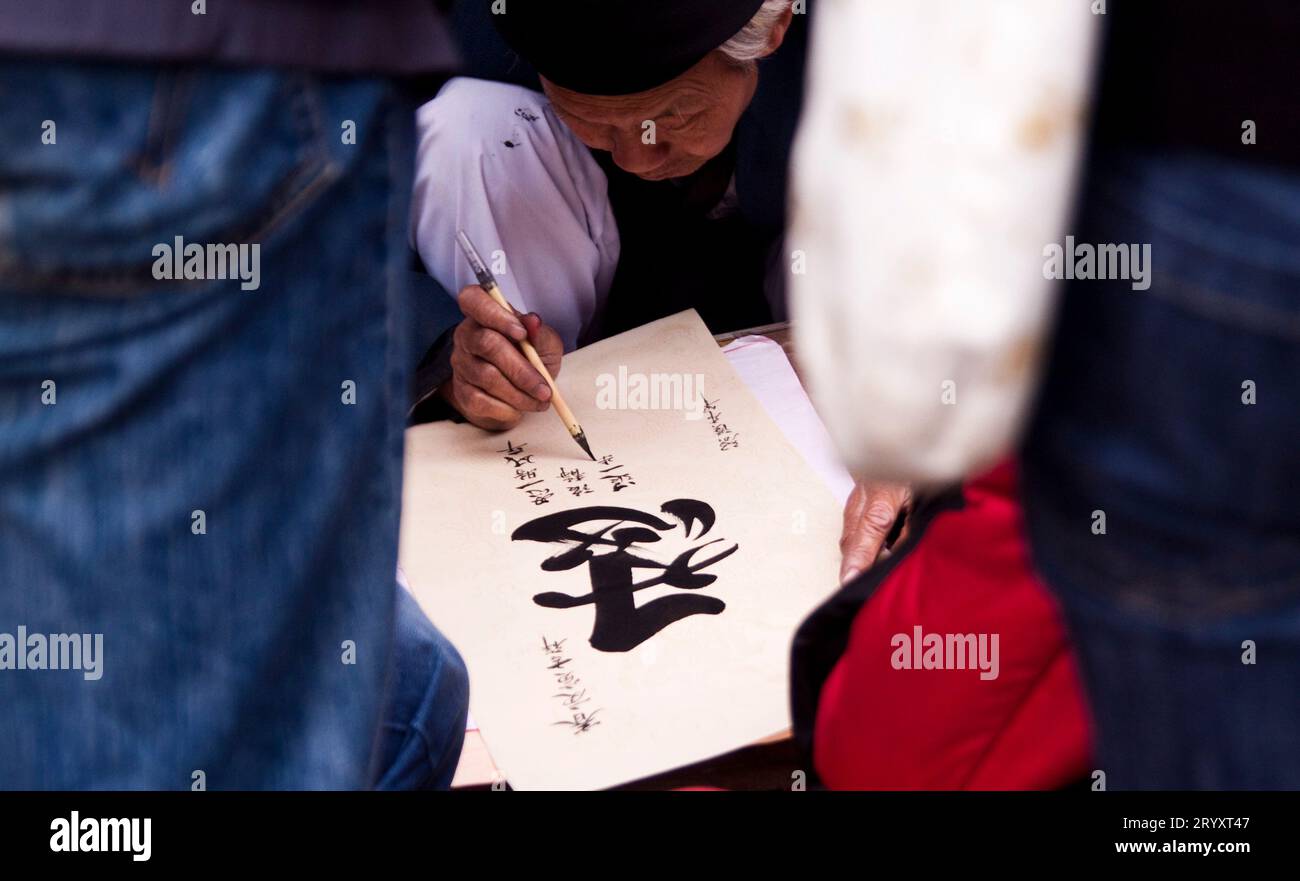 Vicino al Tempio della Letteratura, i calligrafi mostrano le loro abilità. Quegli artisti scrivono caratteri cinesi in una mano decorativa, usando un grande paintbrus Foto Stock