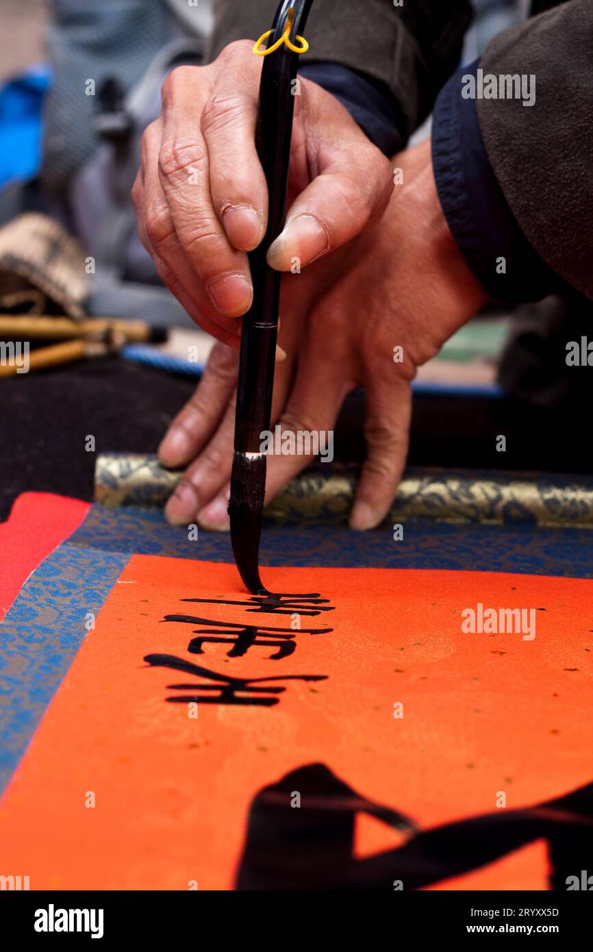 Vicino al Tempio della Letteratura, i calligrafi mostrano le loro abilità. Quegli artisti scrivono caratteri cinesi in una mano decorativa, usando un grande paintbrus Foto Stock