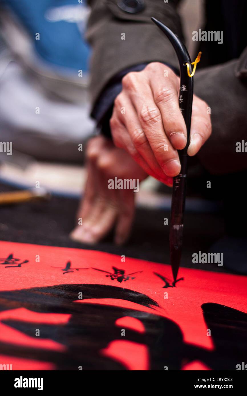 Vicino al Tempio della Letteratura, i calligrafi mostrano le loro abilità. Quegli artisti scrivono caratteri cinesi in una mano decorativa, usando un grande paintbrus Foto Stock