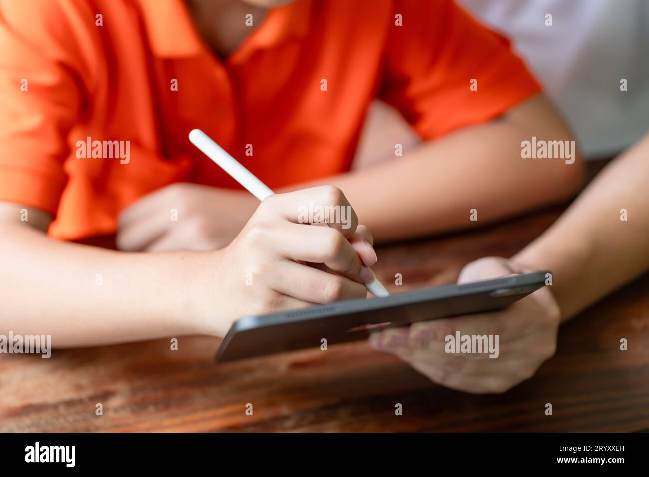 Padre e figlio asiatici che usano tabletÂ insegnare al figlio a disegnare giocare con il tablet digitale alla paternità della scrivania Foto Stock