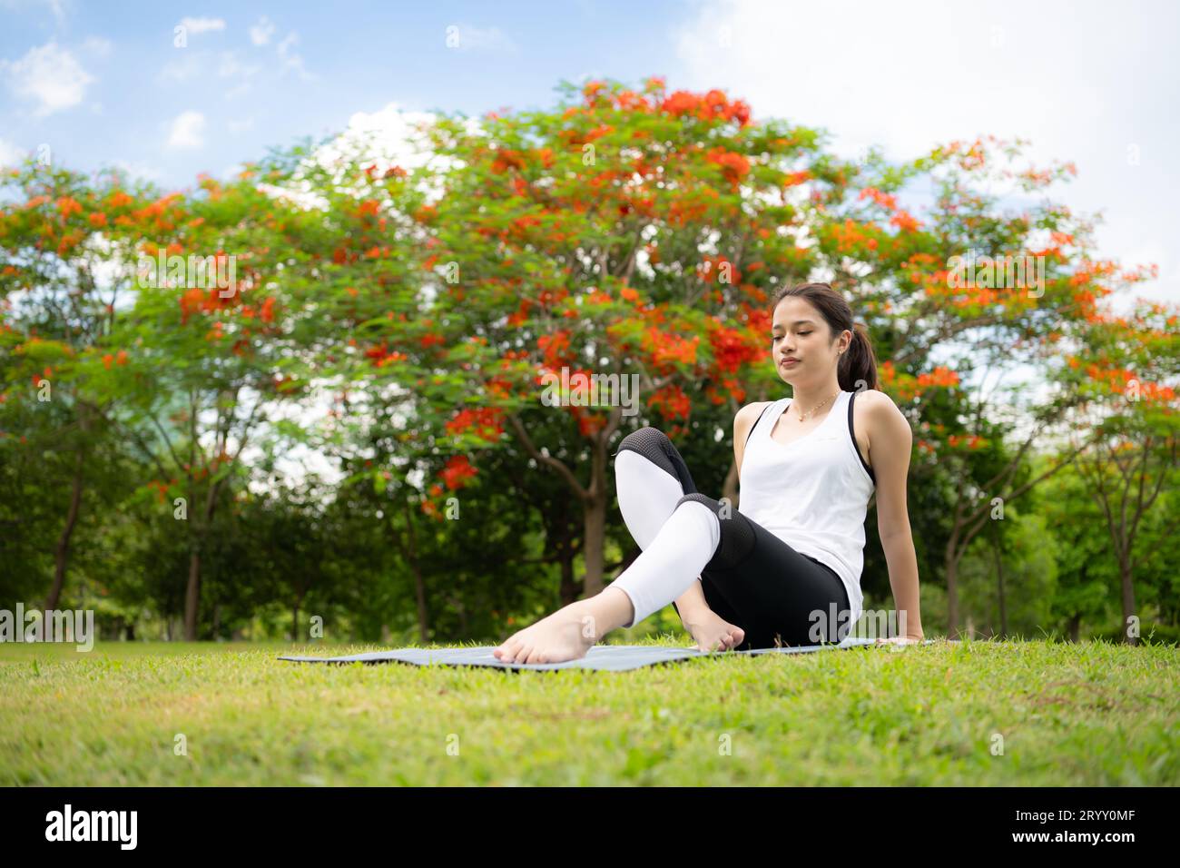 Giovane donna con attività all'aperto nel parco cittadino, lo Yoga è l'attività scelta. Foto Stock