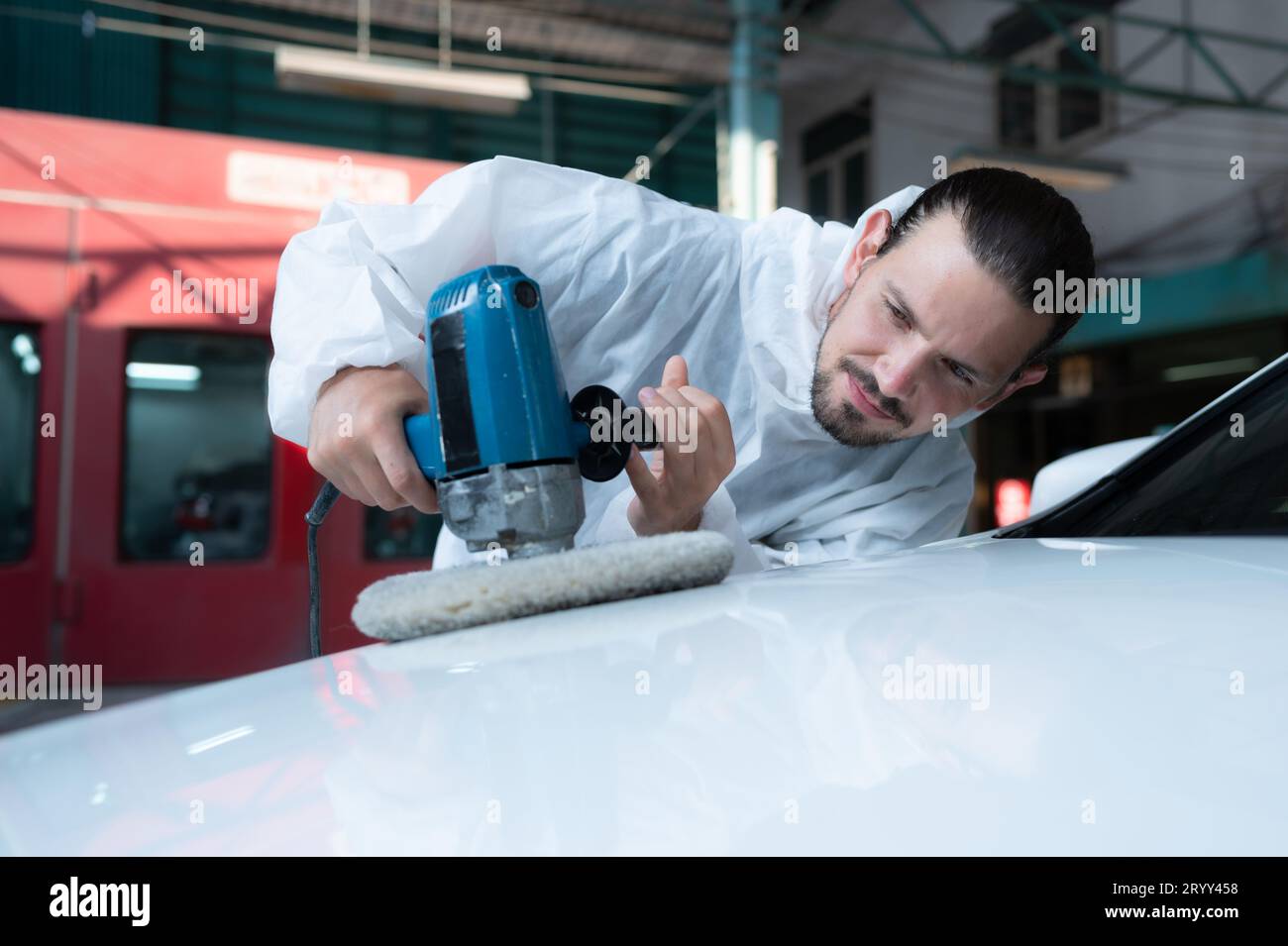 Il meccanico automatico utilizza una lucidatrice elettrica per lucidare la vernice essiccata dell'auto. Dopo aver passato la vernice dalla sala di verniciatura dell'auto Foto Stock