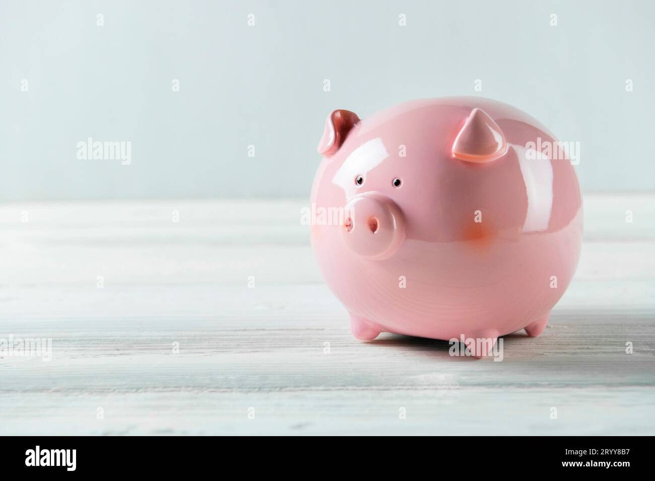 Pink Piggy bank su pavimento in legno bianco. Concetto di risparmio finanziario e di denaro. Spazio di copia Foto Stock