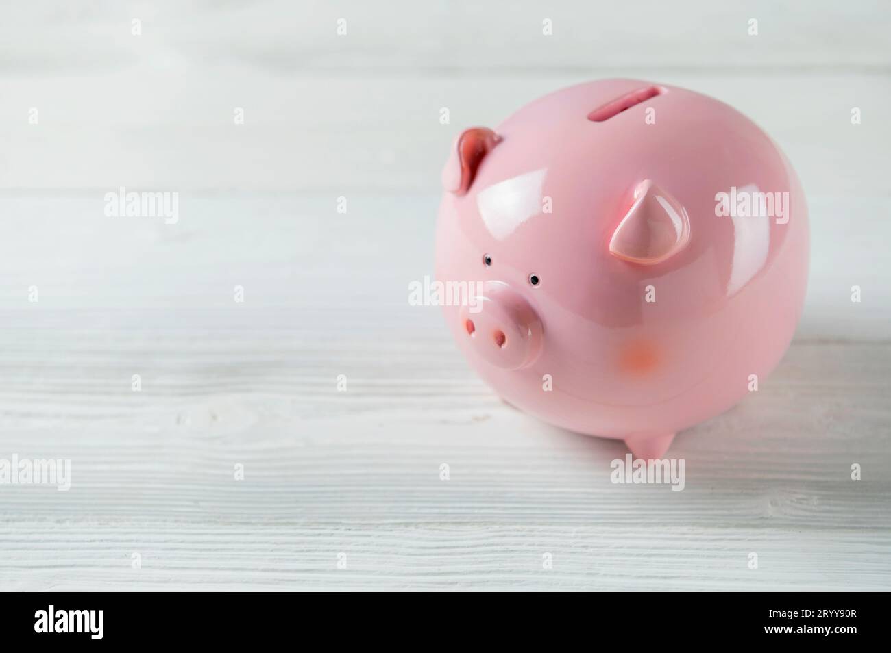 Pink Piggy bank su pavimento in legno bianco. Concetto di risparmio finanziario e di denaro. Spazio di copia Foto Stock
