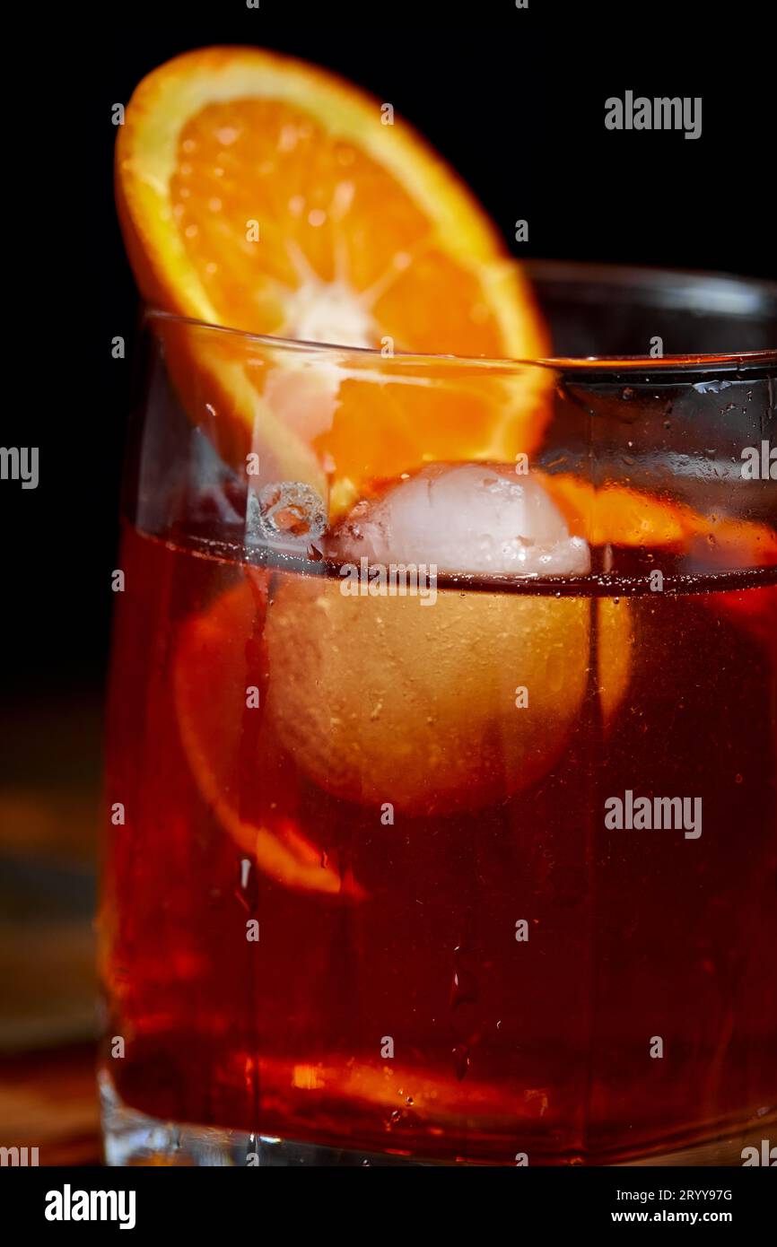 Cocktail alcolico Negroni o cocktail analcolico, bevanda con ghiaccio e scorza d'arancia come decorazione su tavolo di legno Foto Stock