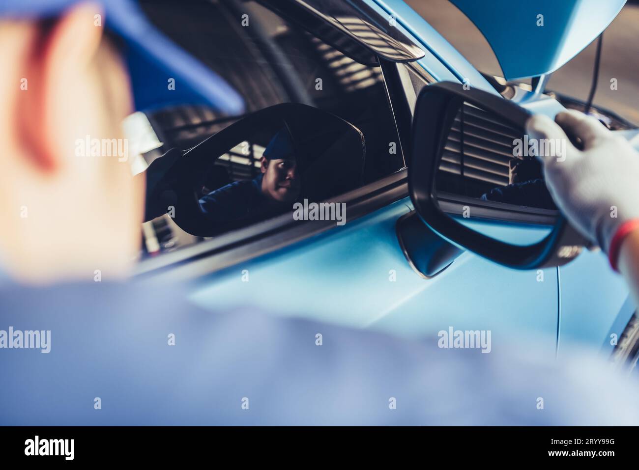 Il tecnico meccanico sta guardando lo specchietto retrovisore per controllare il veicolo in manutenzione in base all'ordine di richiesta di rimborso del cliente in auto r Foto Stock