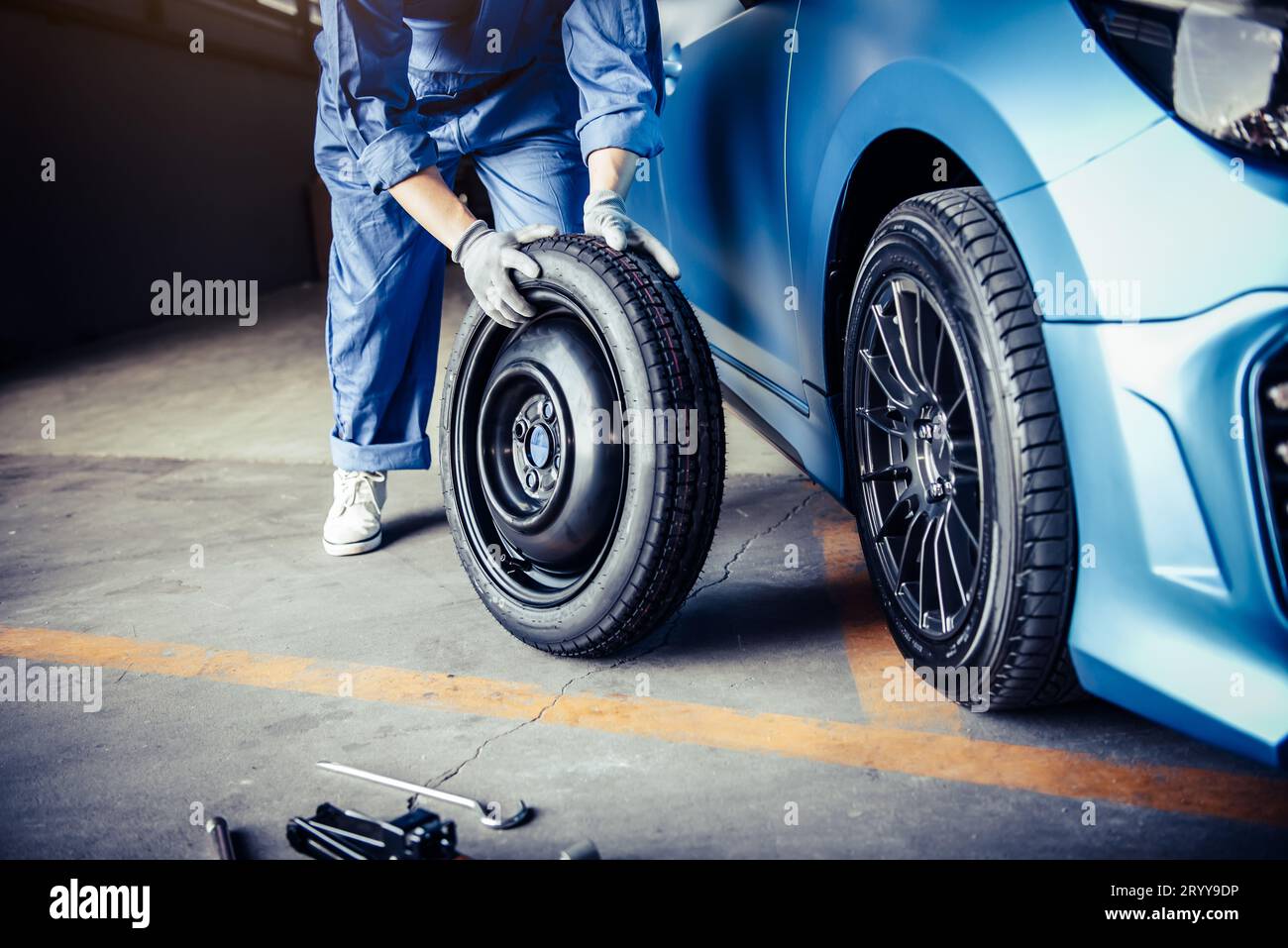 Meccanici per la sostituzione degli pneumatici presso l'officina di riparazione auto. Concetto di persone che lavorano per il settore trasporti e affari. Tecnicia automobilistica Foto Stock