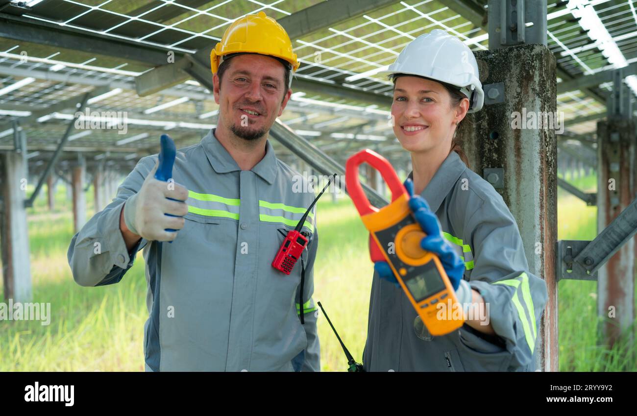 Un team di ingegneri elettrici sta ispezionando e manutenendo i pannelli solari in un sito di pannelli solari nel mezzo di cento acri Foto Stock
