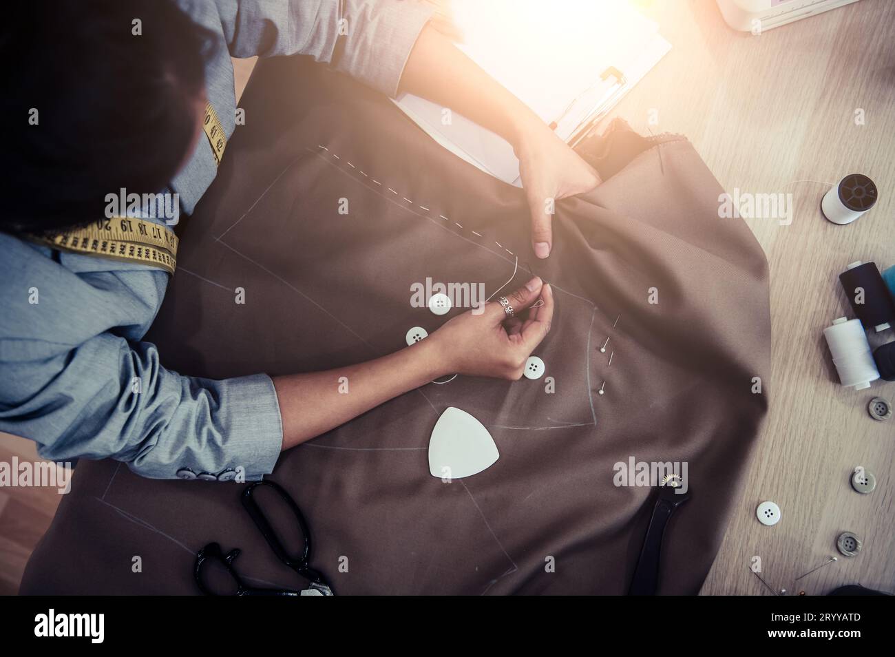 Vista dall'alto della splendida sartoria che cuce il tessuto con la mano. Stilista sartoriale o fognatura in uno studio di progettazione in officina Foto Stock