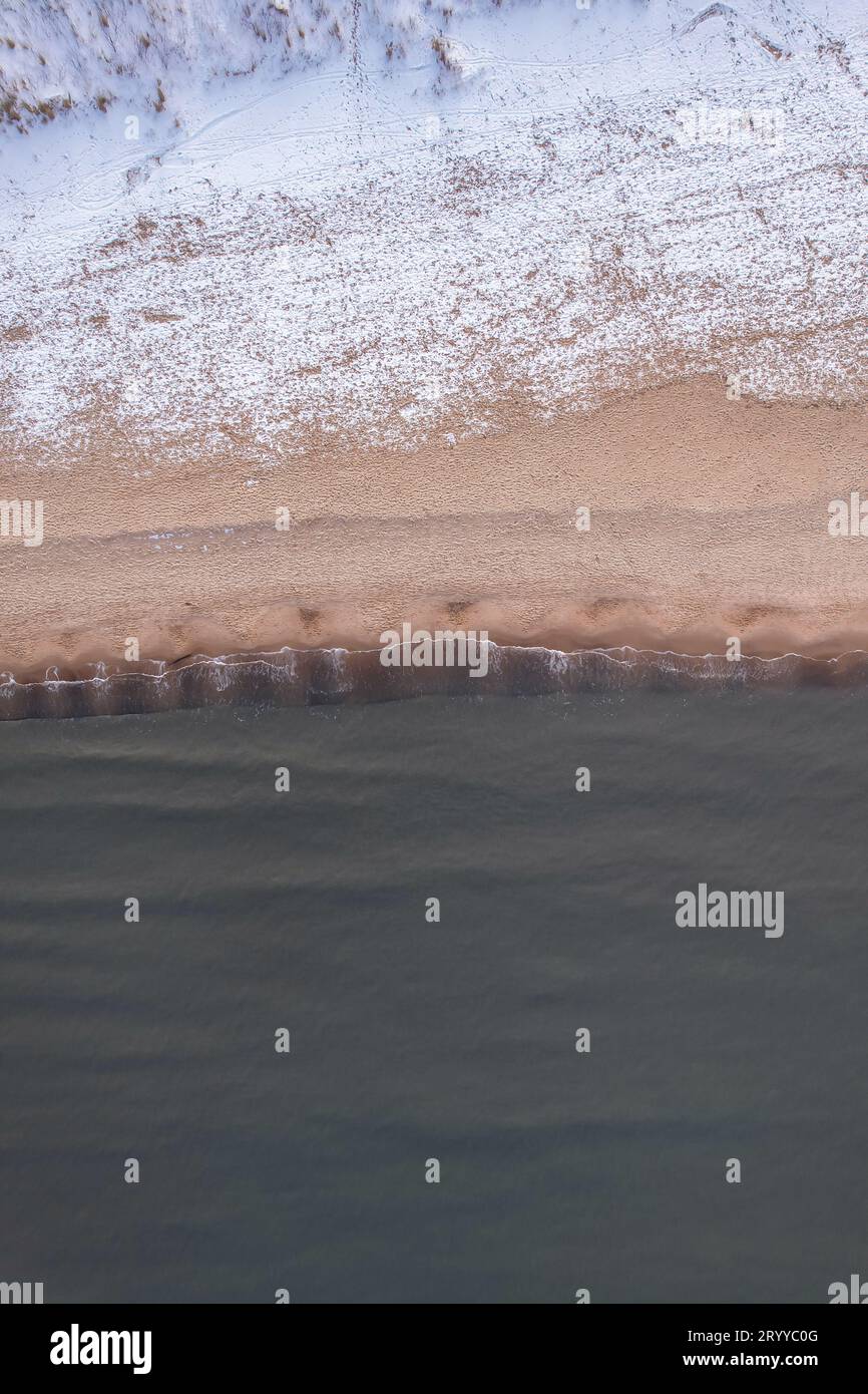 Inverno nella fredda spiaggia innevata del Mar Baltico a Danzica. Vista aerea della spiaggia innevata e delle dune e del paesaggio naturale scuro e calmo Foto Stock