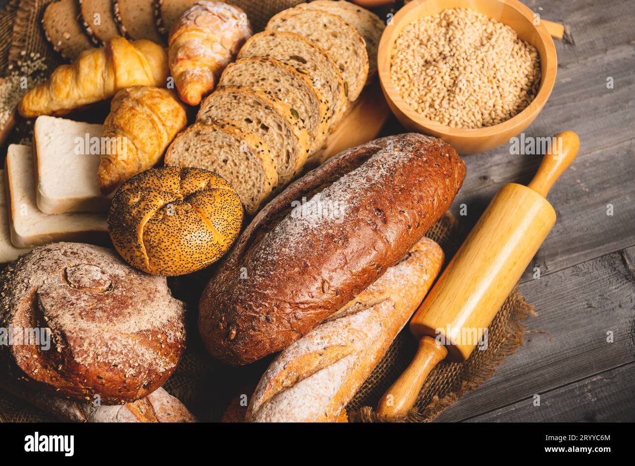 Diversi tipi di pane con cereali integrali nutrizionali su fondo di legno. Cibo e panificio in cucina. Colazione deliziosa Foto Stock