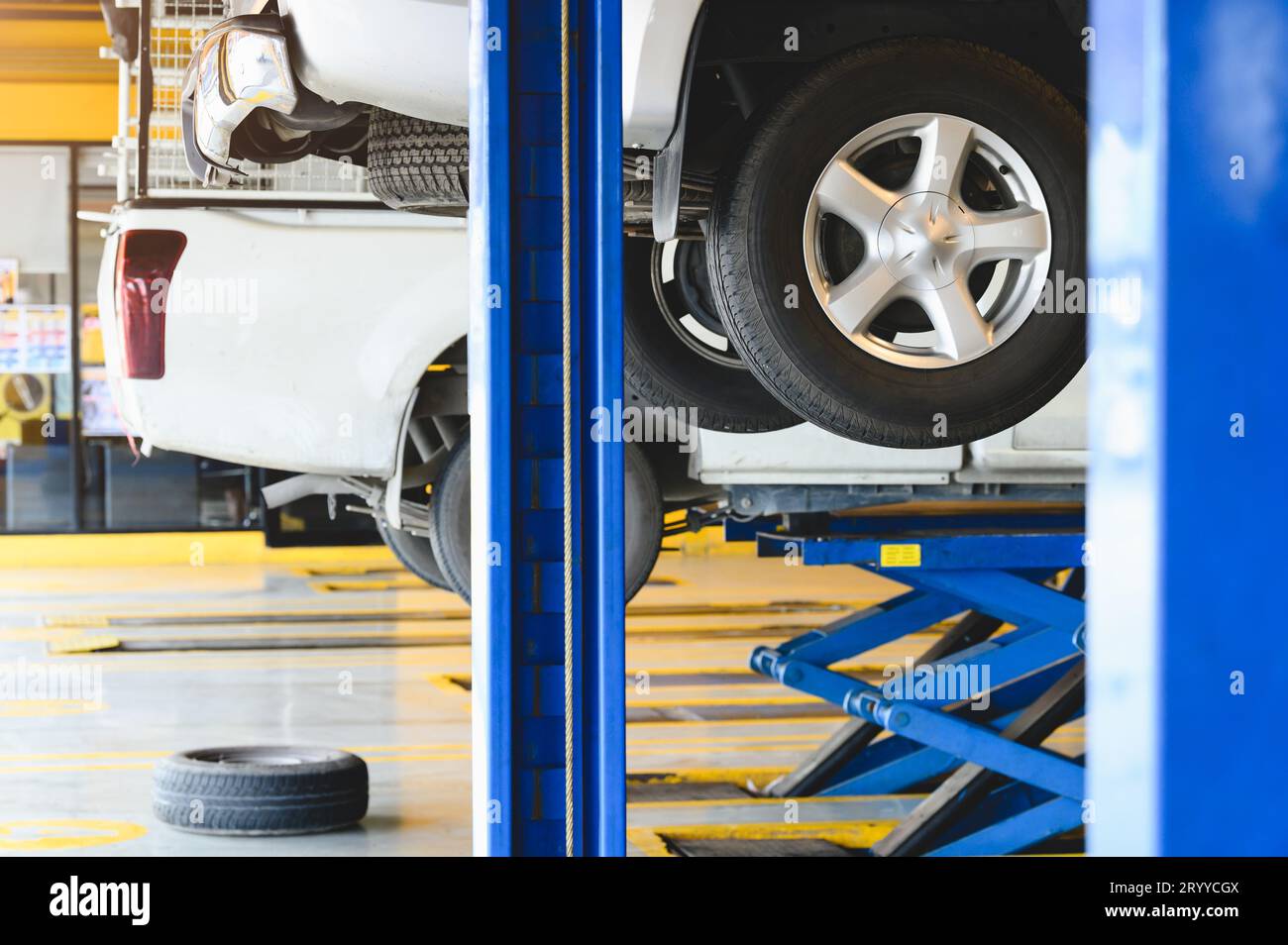 Auto raccoglitore sollevato in ascensore per auto in auto service garage centro per la sostituzione dei pneumatici. Auto automobilistico di riparazione e di manutenzione del concetto. Foto Stock