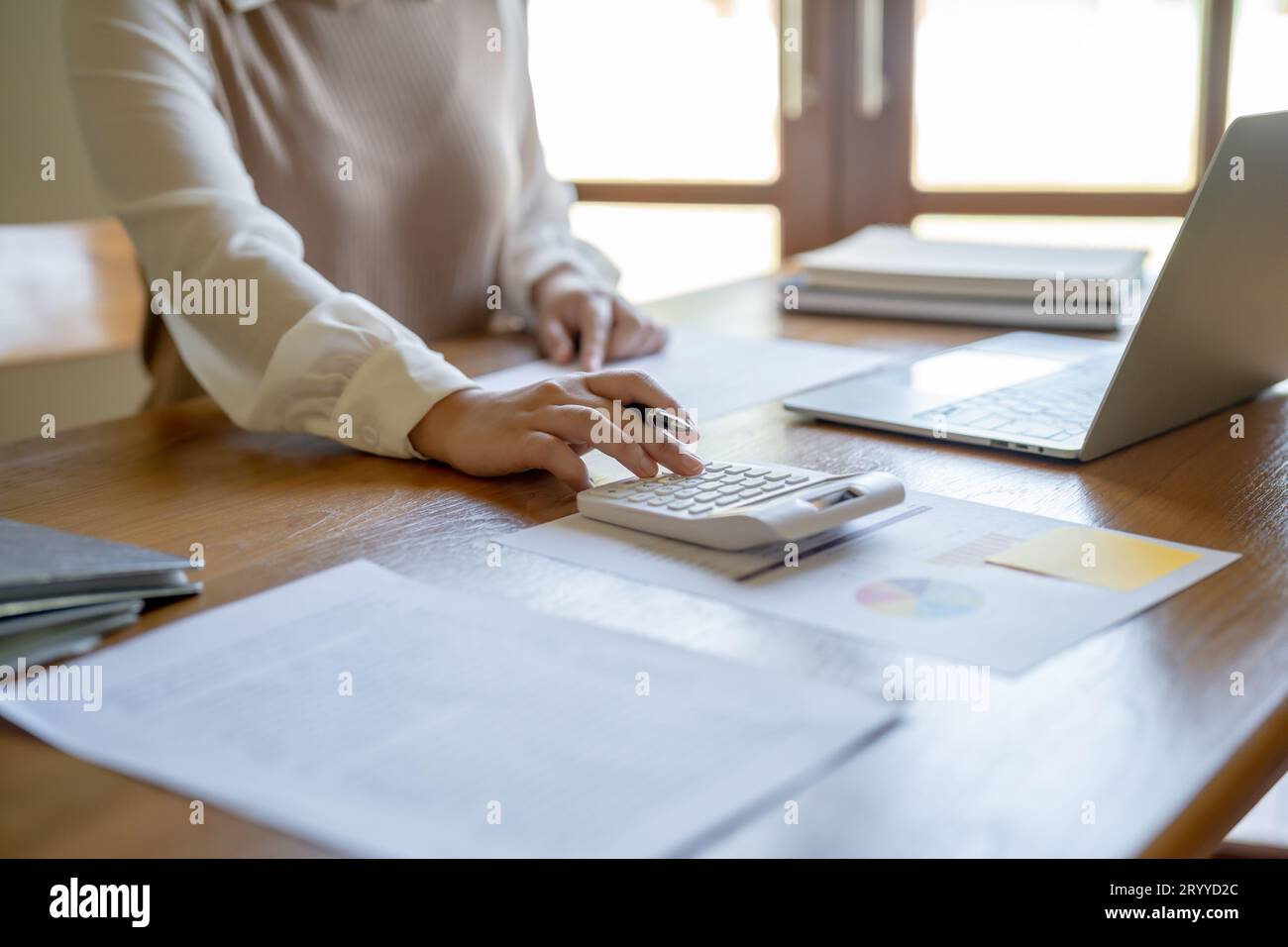 Imprenditrice contabile che analizza i grafici di investimento fattura e preme i pulsanti di calcolo sui documenti. Contabilità Foto Stock