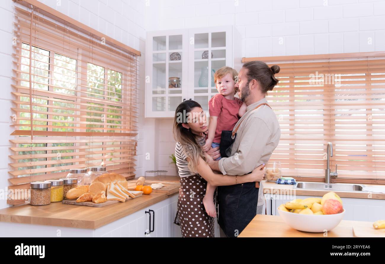 Mamma e papà nella cucina della casa con i loro figli piccoli. Divertiti a preparare la cena insieme. Foto Stock