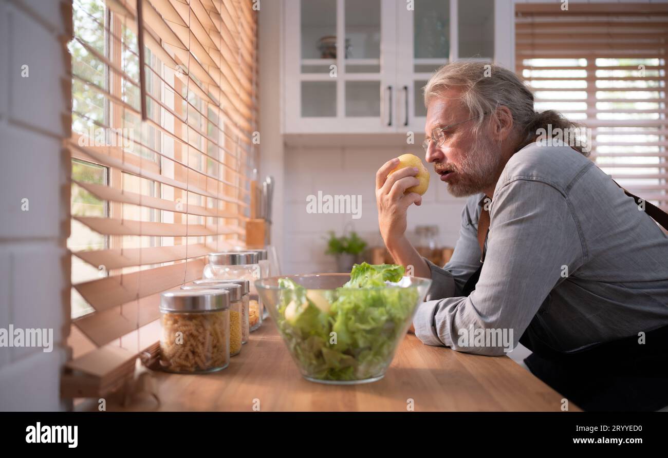 Nonno in cucina con luce naturale, si prepara per la cena del giorno per la famiglia. Foto Stock