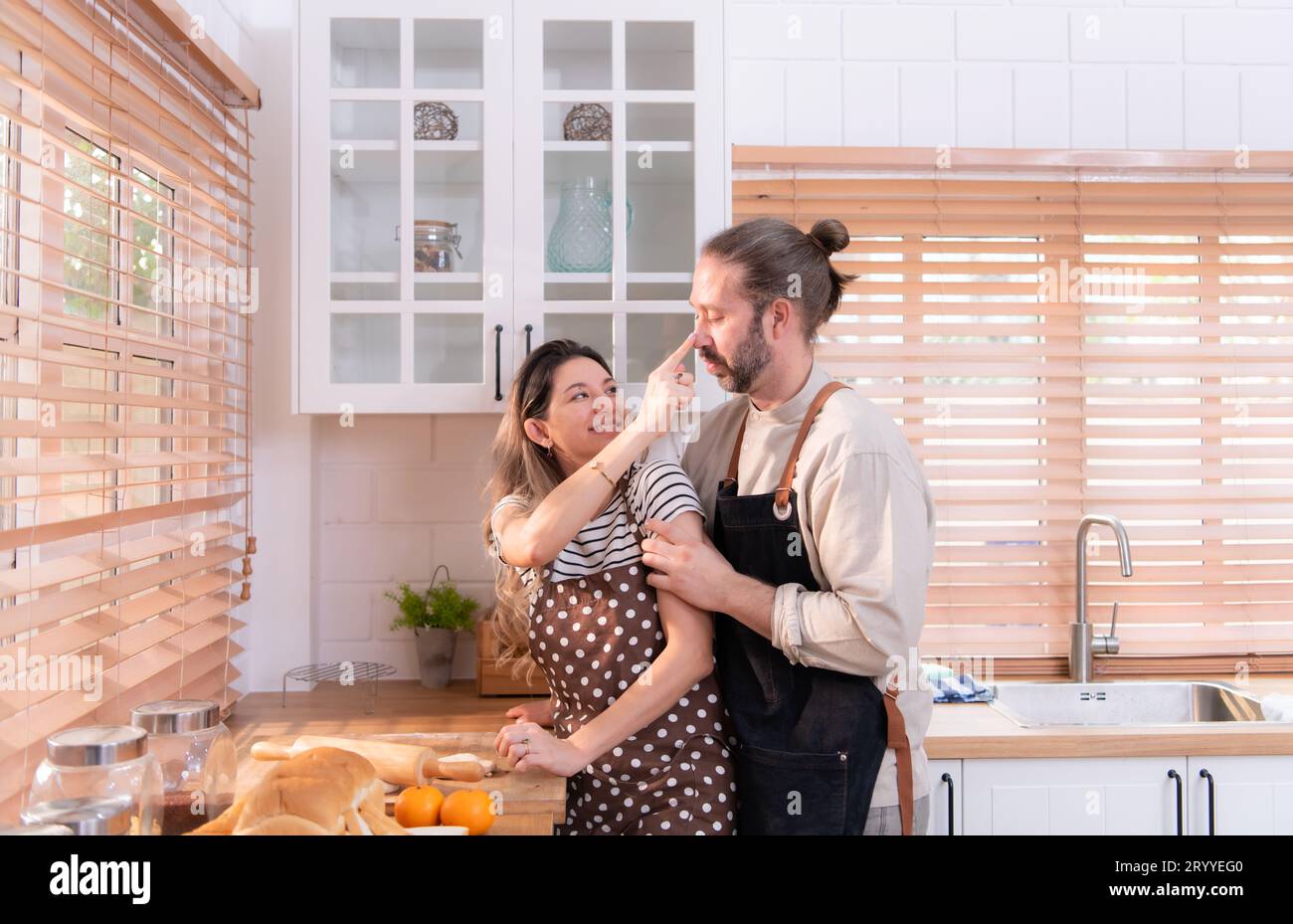 Padre e madre nella cucina della casa si divertono a preparare la cena insieme, aspettando il ritorno del giovane da Foto Stock