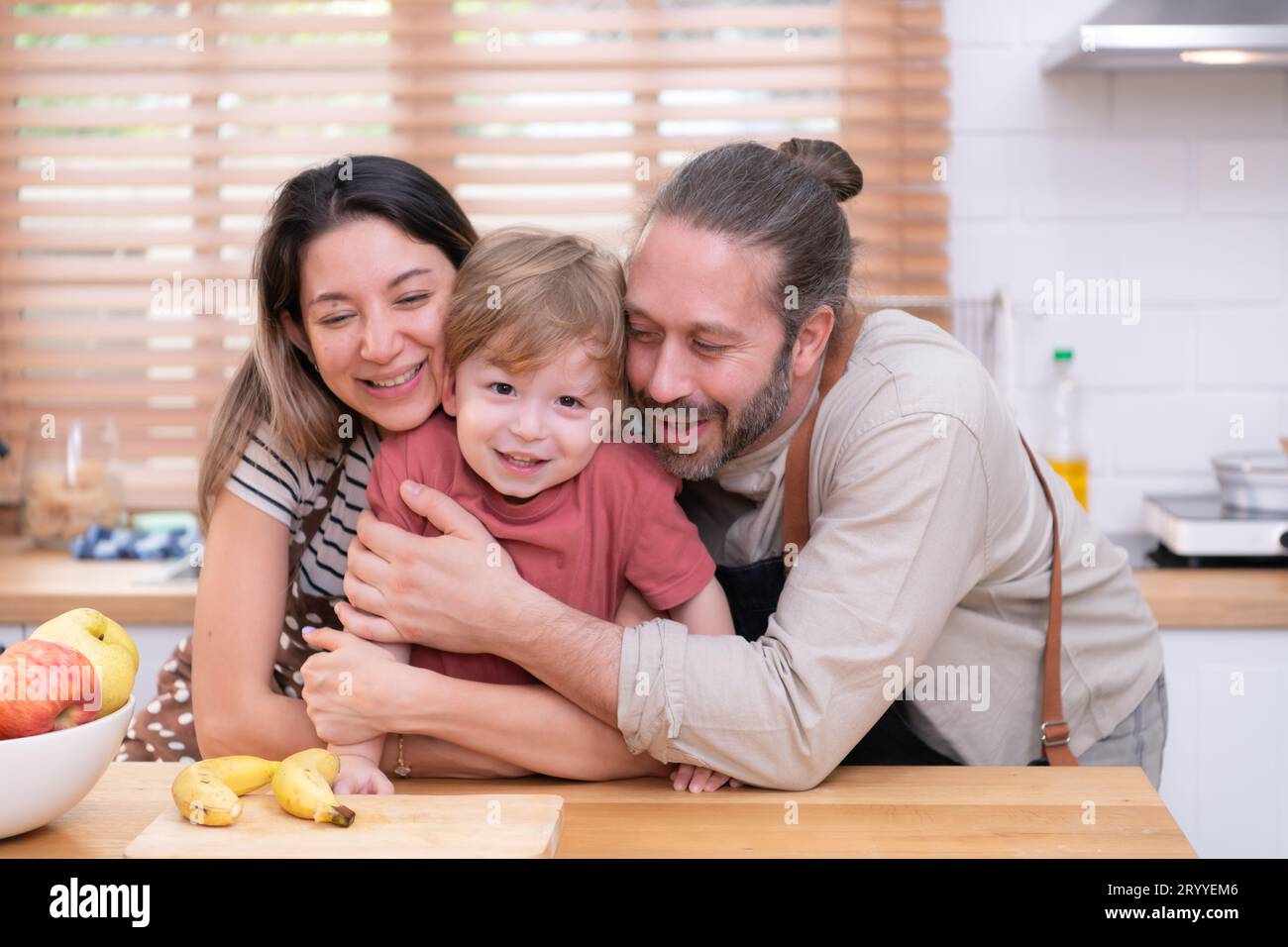 Mamma e papà nella cucina della casa con i loro figli piccoli. Divertiti a preparare la cena insieme. Foto Stock