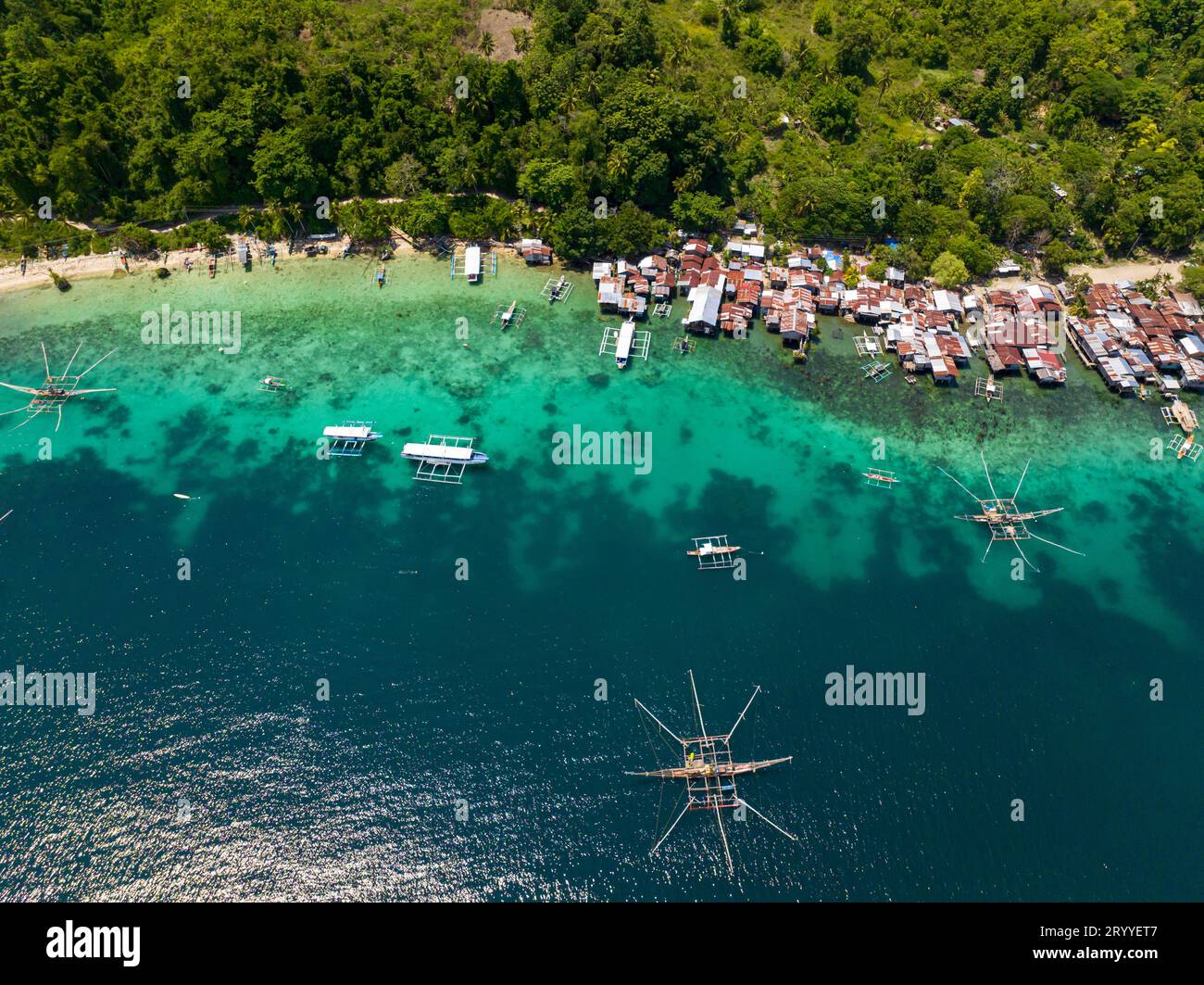 Riflesso della luce del sole sulla barca da pesca e sull'acqua azzurra. Case sull'acqua a Samal Island. Davao, Filippine. Foto Stock