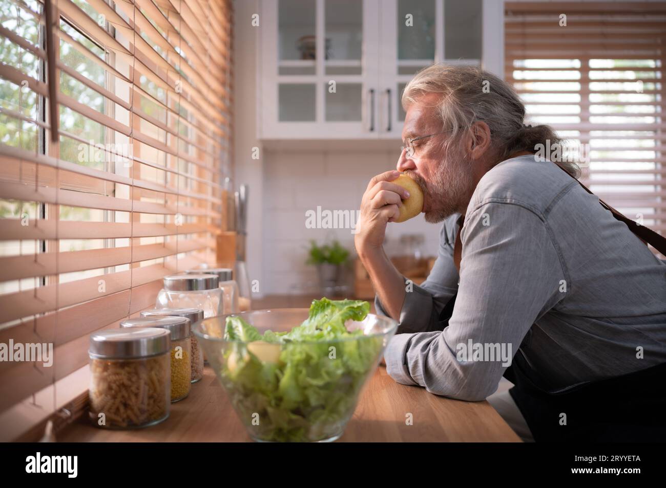 Nonno in cucina con luce naturale, si prepara per la cena del giorno per la famiglia. Foto Stock