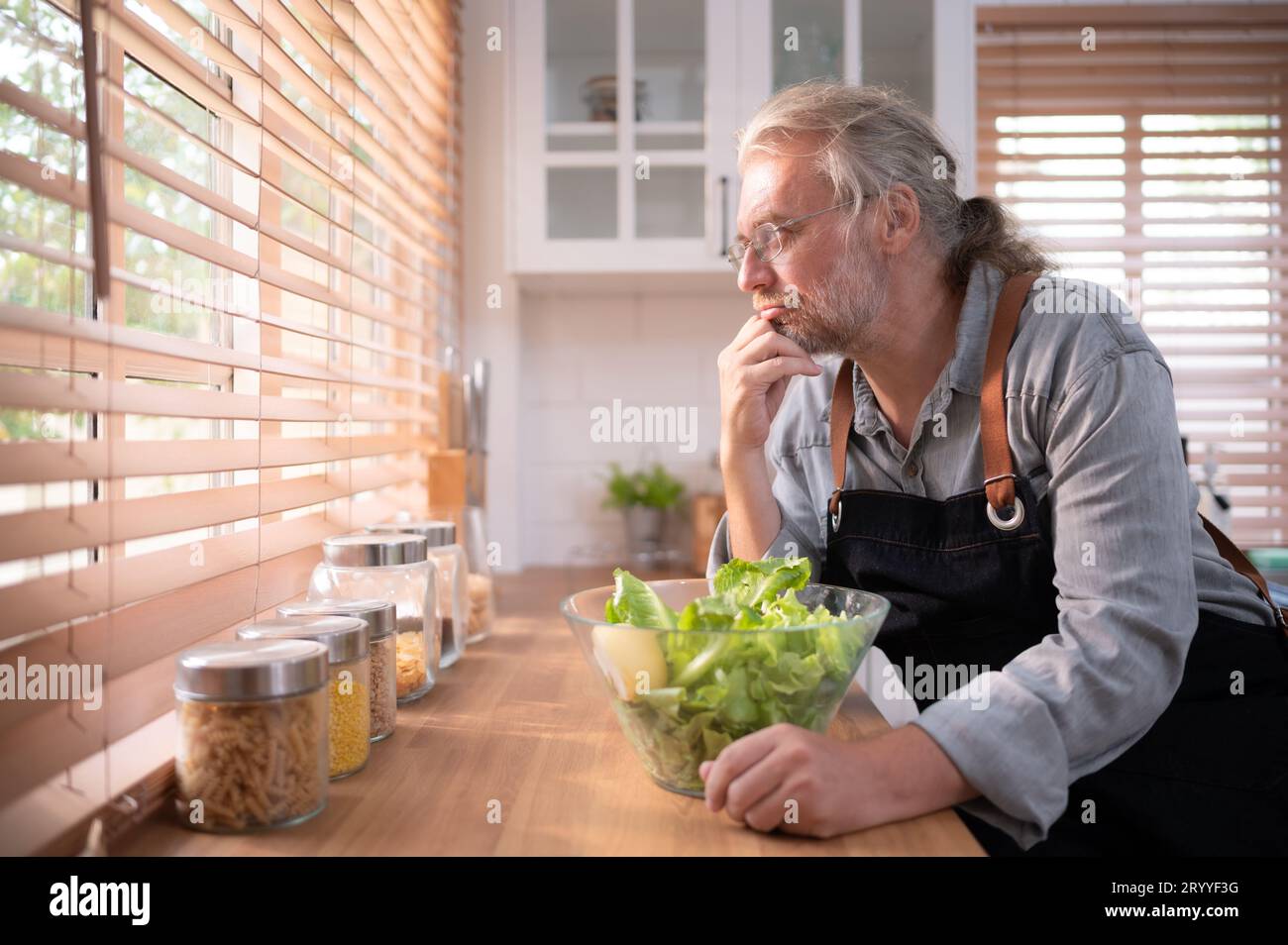 Nonno in cucina con luce naturale, si prepara per la cena del giorno per la famiglia. Foto Stock