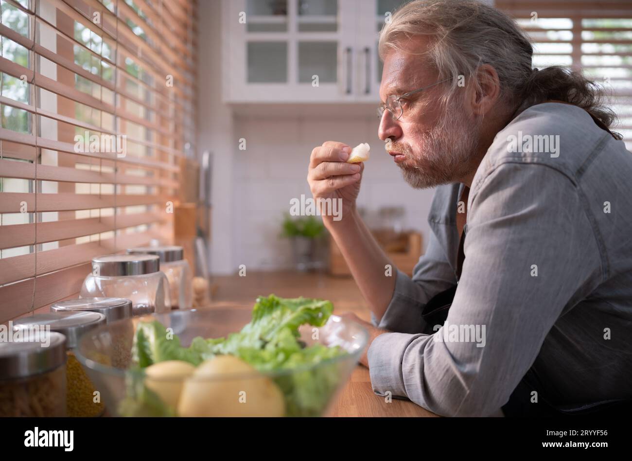 Nonno in cucina con luce naturale, si prepara per la cena del giorno per la famiglia. Foto Stock