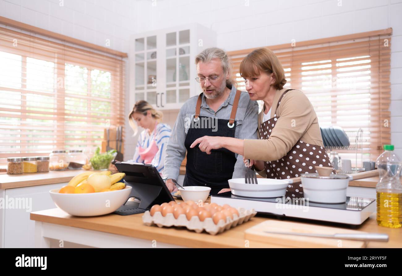 Nonni con nipoti e figlia si riuniscono in cucina per preparare la cena del giorno. Foto Stock