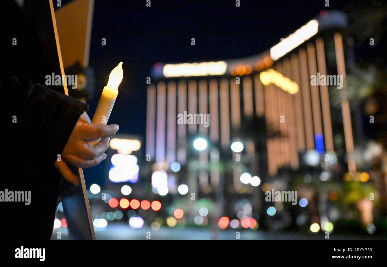 Las Vegas, Nevada, Stati Uniti. 1 ottobre 2023. Una donna tiene una candela commemorativa mentre espone una fotografia di una delle vittime della sparatoria di massa di Las Vegas del 2017 il 1° ottobre 2023, a Las Vegas, Nevada. Circa 150 persone hanno sfidato la pioggia inaspettata e il vento freddo nell'ex villaggio di Las Vegas per onorare e ricordare le 58 persone uccise sei anni fa da un uomo armato solitario durante il Route 91 Harvest Music Festival dal 32° piano del Mandalay Bay Resort and Casino il 1° ottobre 2017. 58 persone morirono inizialmente con altre due persone che morirono più tardi a causa delle loro ferite, m Foto Stock