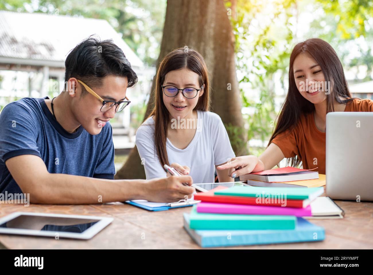 Tre asiatici giovani studenti del campus godetevi il tutoraggio e la lettura di libri insieme. L'amicizia e il concetto di istruzione. Il campus della scuola e università del tema. Hap Foto Stock