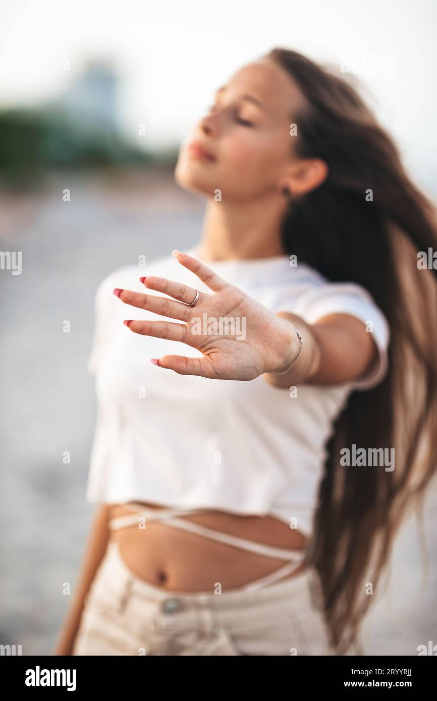 Adorabile giovane ragazza con bellissimi capelli lunghi goditi una vacanza tropicale sulla spiaggia. La ragazza in riva al mare al tramonto Foto Stock