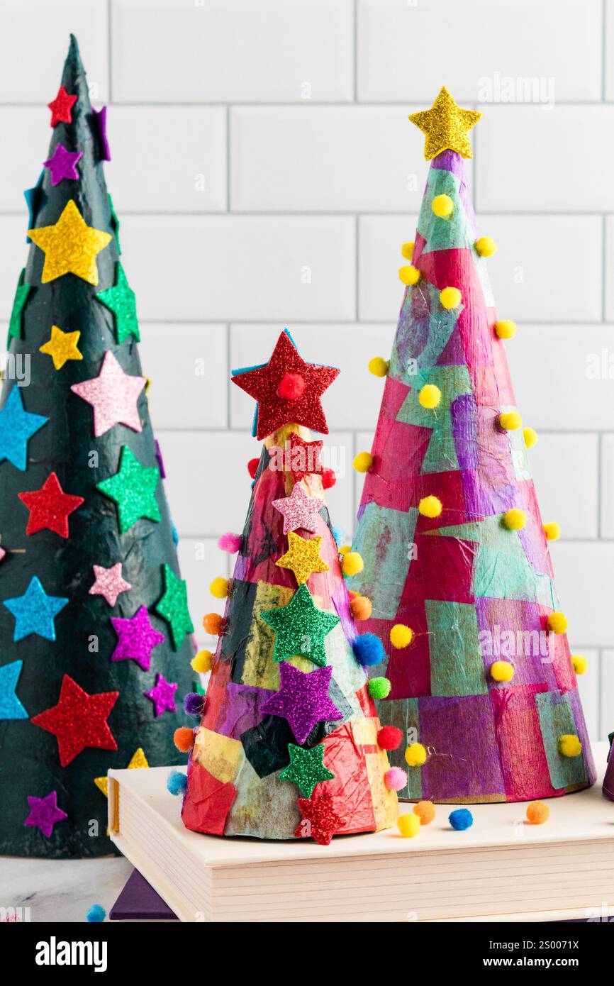 Alberi di Natale a cono di carta colorata con stelle e pompon Foto Stock